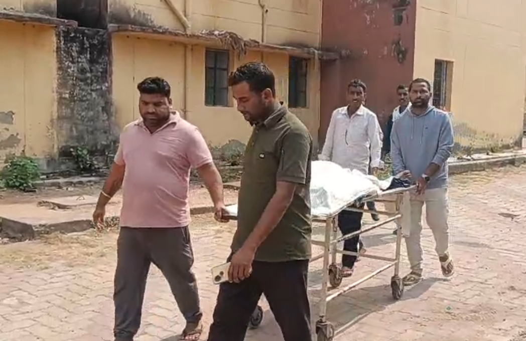 People carrying a stretcher outdoors.